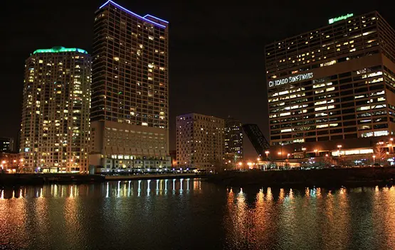 Chicago skyline at night with illuminated skyscrapers reflecting on the river water