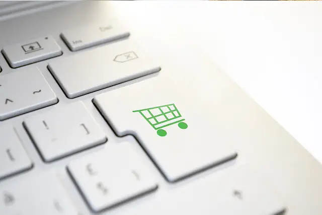 White keyboard with green shopping cart icon on enter key for online shopping