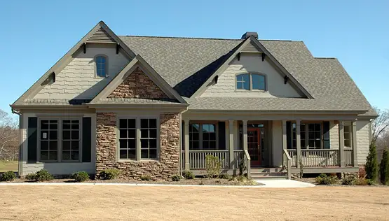 Large two-story craftsman style house with stone accents, covered front porch, and gray shingle roof