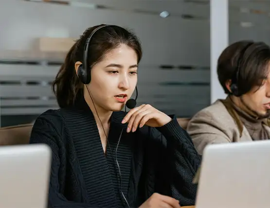 Customer service representative wearing headset working at computer in modern office