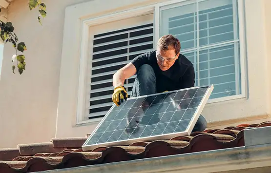 Technician installing solar panel on residential tile roof near window
