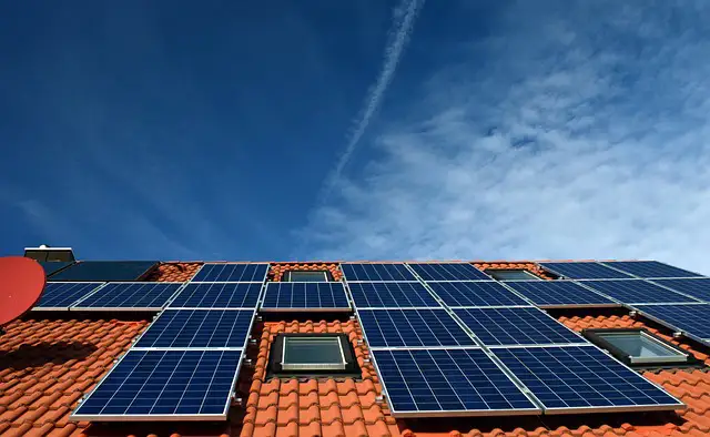 Solar panels installed on orange tile roof against blue sky with skylights visible