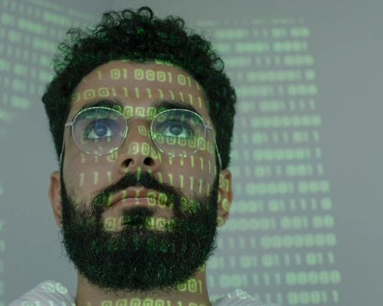 Man wearing glasses with binary code and digital data projected on face and background